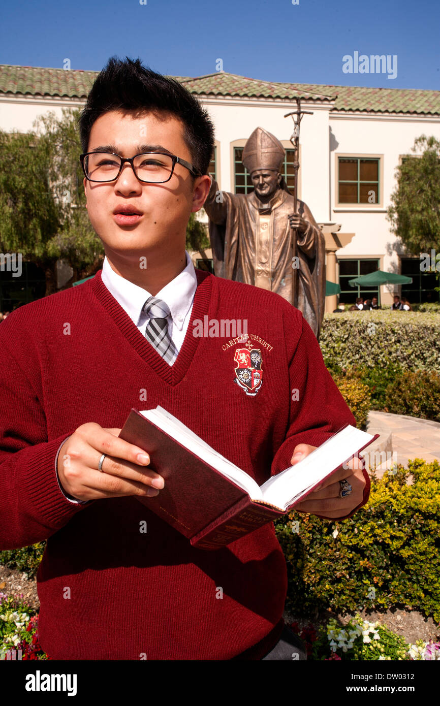 Une asiatique en uniforme des étudiants américains se lit la Bible sur le campus d'une école secondaire privée catholique à San Juan Capistrano, CA. Banque D'Images