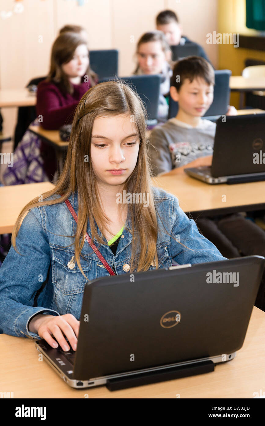 Des élèves du premier cycle du secondaire (environ 12 ans) travailler avec leur ordinateur portable dans leur classe. Banque D'Images