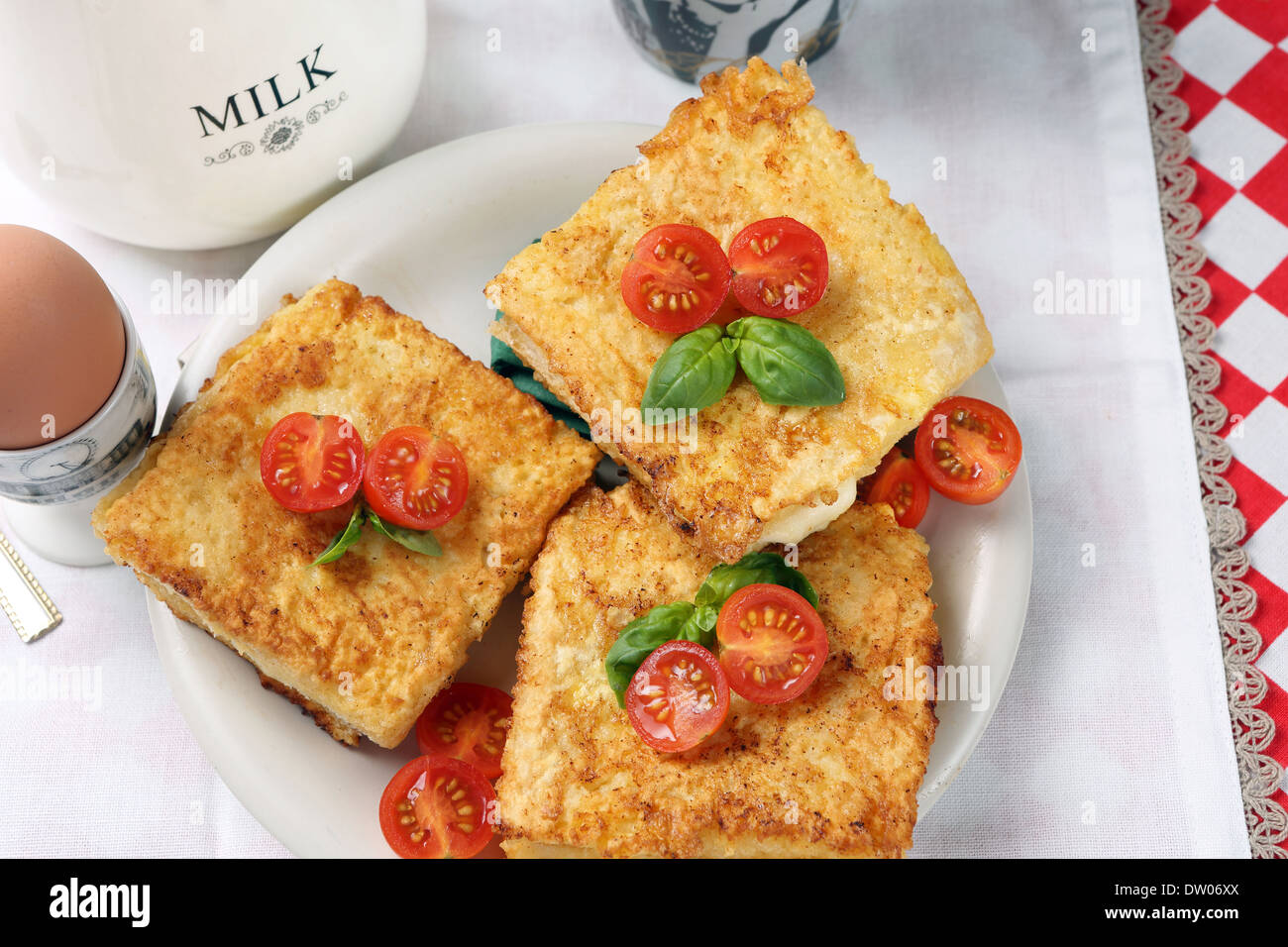 Toast avec du fromage et tomates, servi avec des oeufs au plat et une tasse de lait Banque D'Images