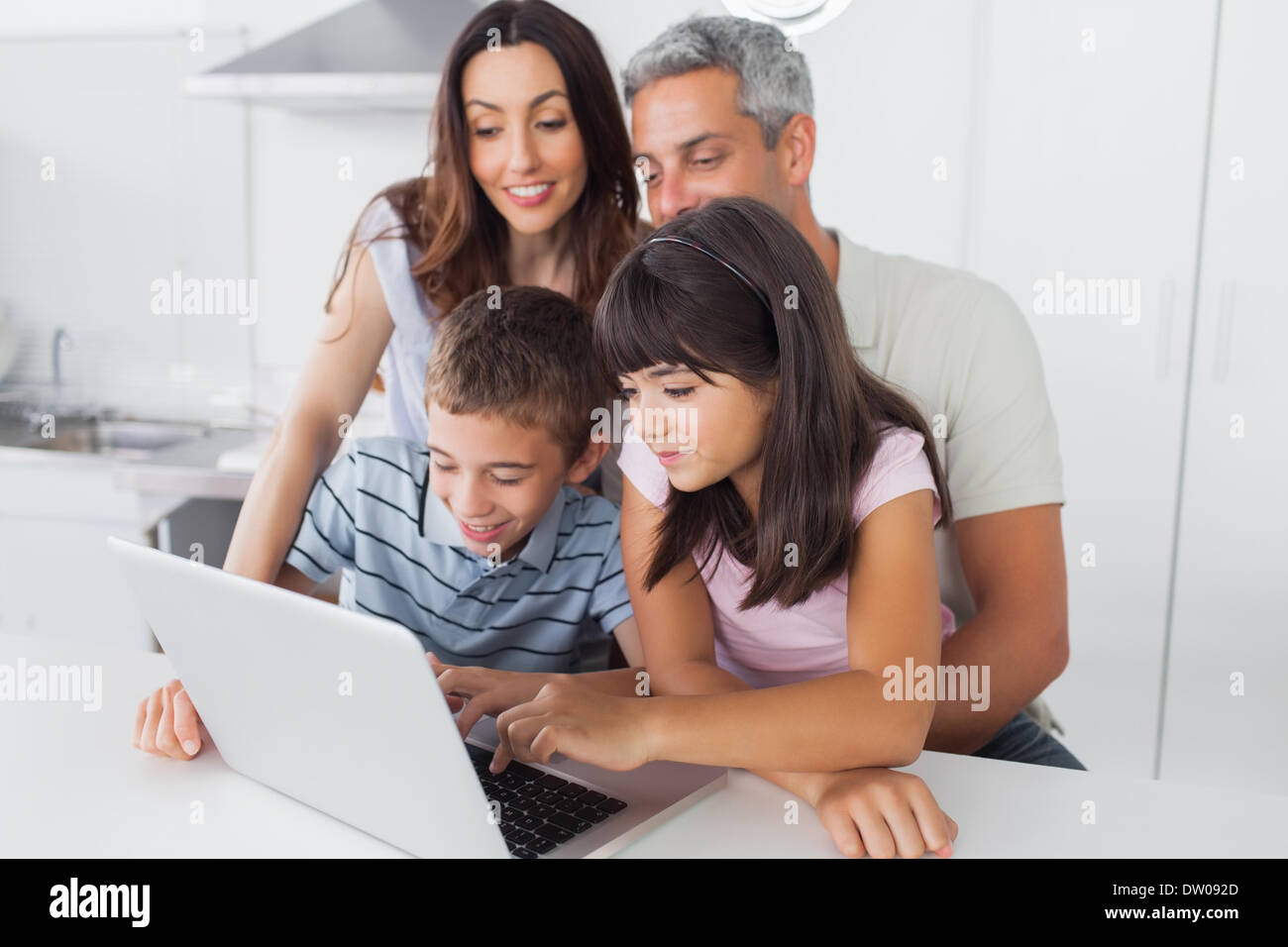 Family sitting in kitchen en utilisant leur ordinateur portable Banque D'Images