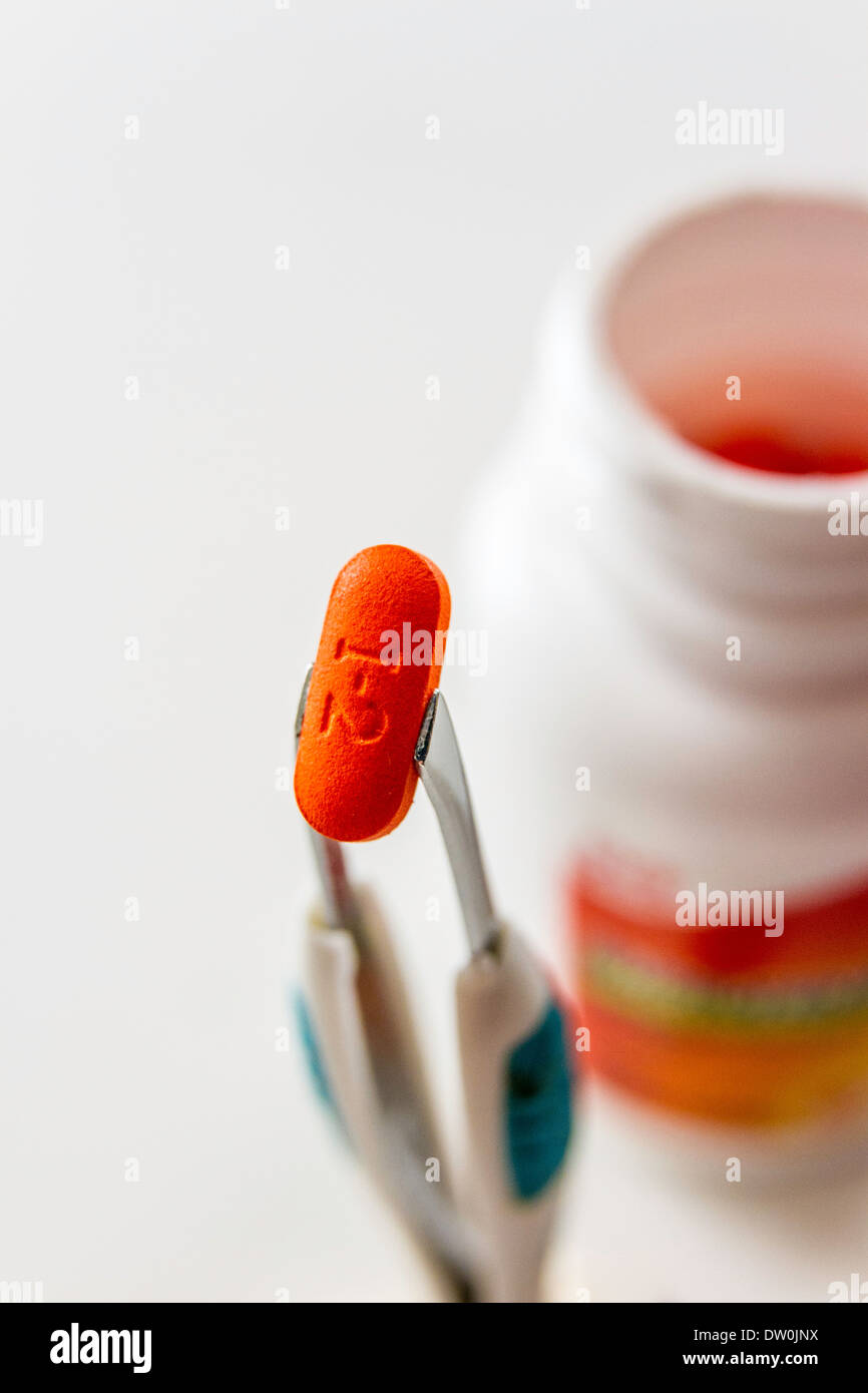 Une marque générique de l'Ibuprofène en comprimé avec une bouteille tenue par pincettes Banque D'Images
