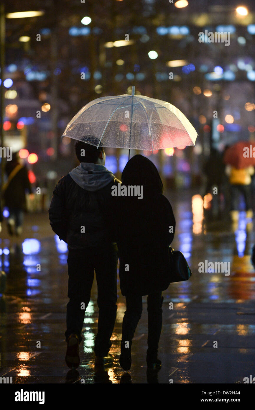 Beijing, Chine. Feb 26, 2014. Un couple marcher avec un parapluie sous la  pluie dans une zone commerciale, de Xidan à Beijing, capitale de la Chine,  26 février 2014. Beijing a vu