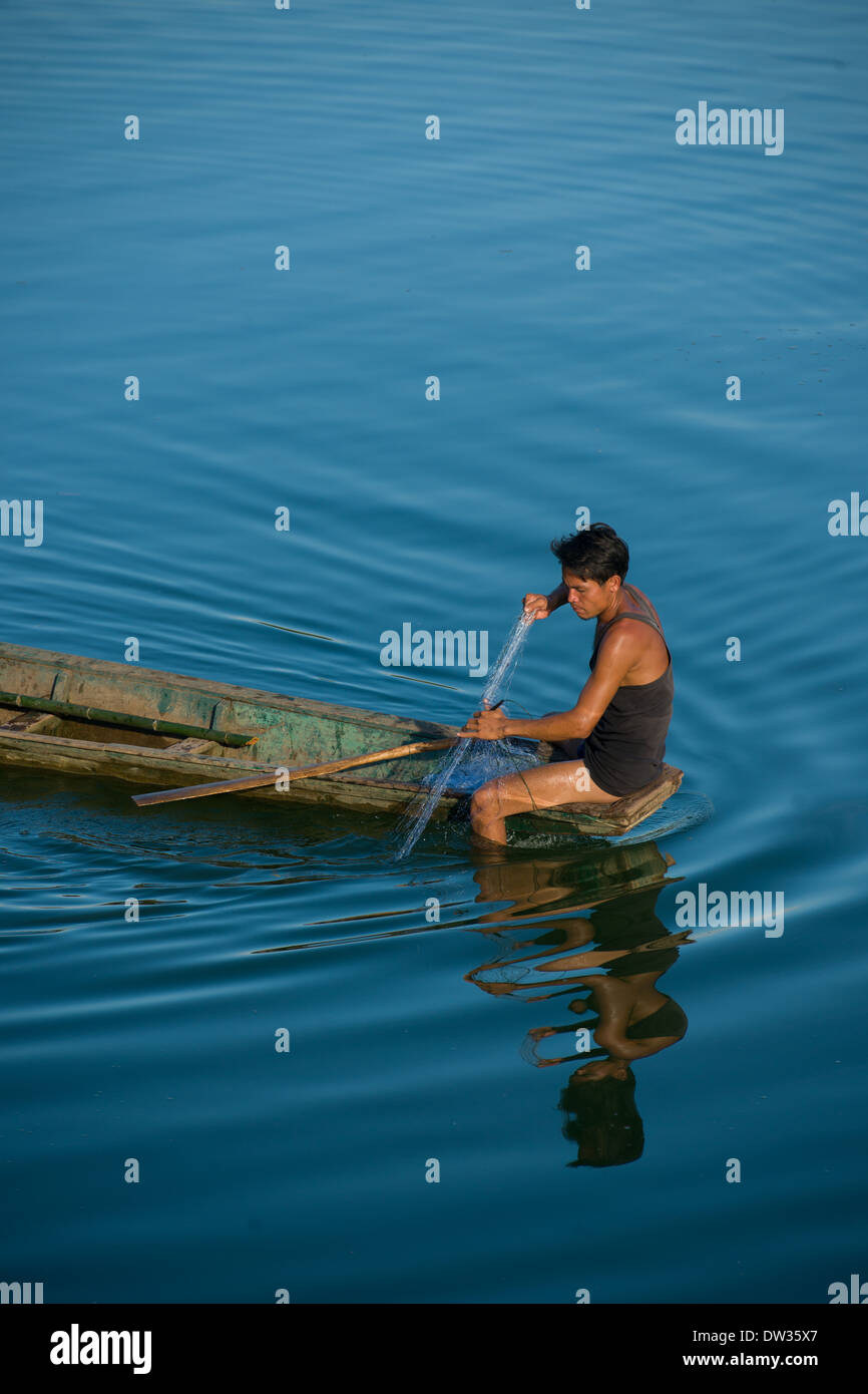 Transport de pêcheur dans son filet de son bateau sur un affluent de la rivière Nam Xong, entre Vang Vieng, Laos Nam Ngum et Banque D'Images