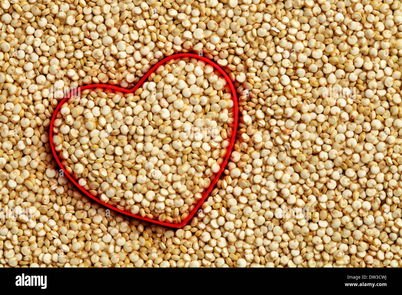Forme de coeur rouge sur fond de quinoa cru Banque D'Images
