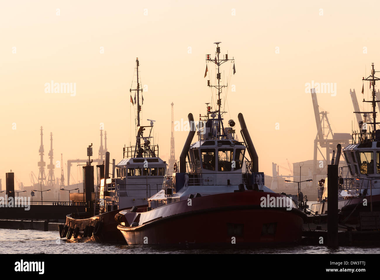 Les remorqueurs dans le port amarré au quai au coucher du soleil Banque D'Images