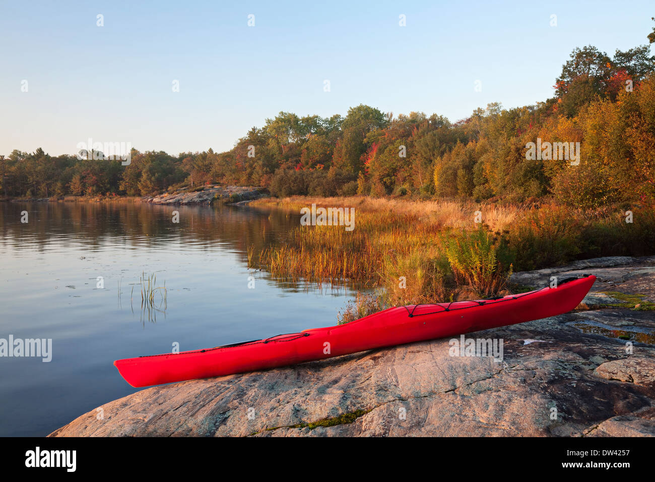 Un kayak repose sur un rivage rocailleux au lever du soleil dans le Massasauga Parc Provincial de l'Ontario, Canada. Banque D'Images