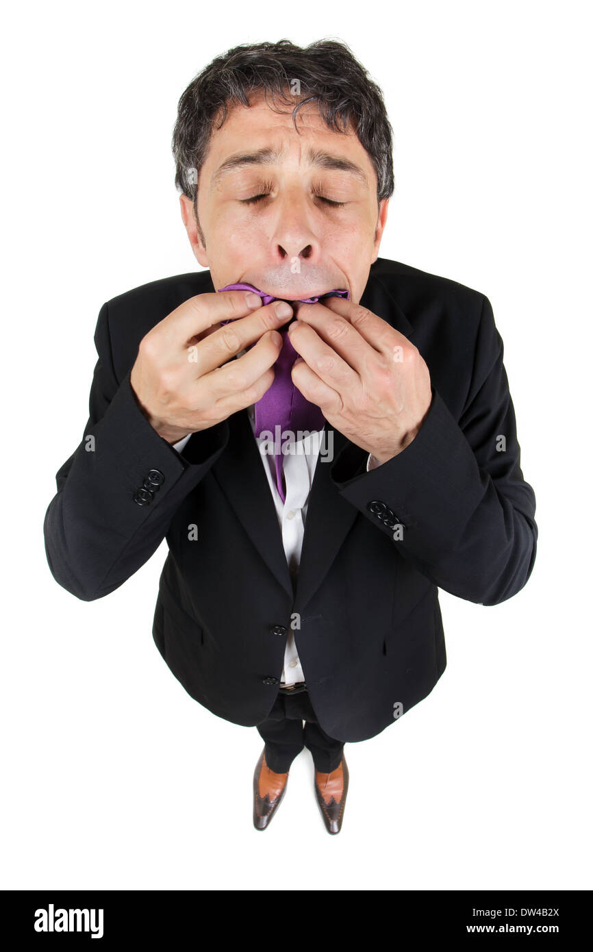 Fun high angle conceptuel portrait d'un homme d'affaires élégant standing looking up avec ses yeux fermés de manger sa cravate Banque D'Images