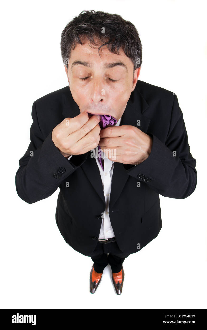 High angle conceptuel pleine longueur portrait d'un homme d'âge moyen élégant pousser sa cravate mauve dans sa bouche avec une douleur Banque D'Images