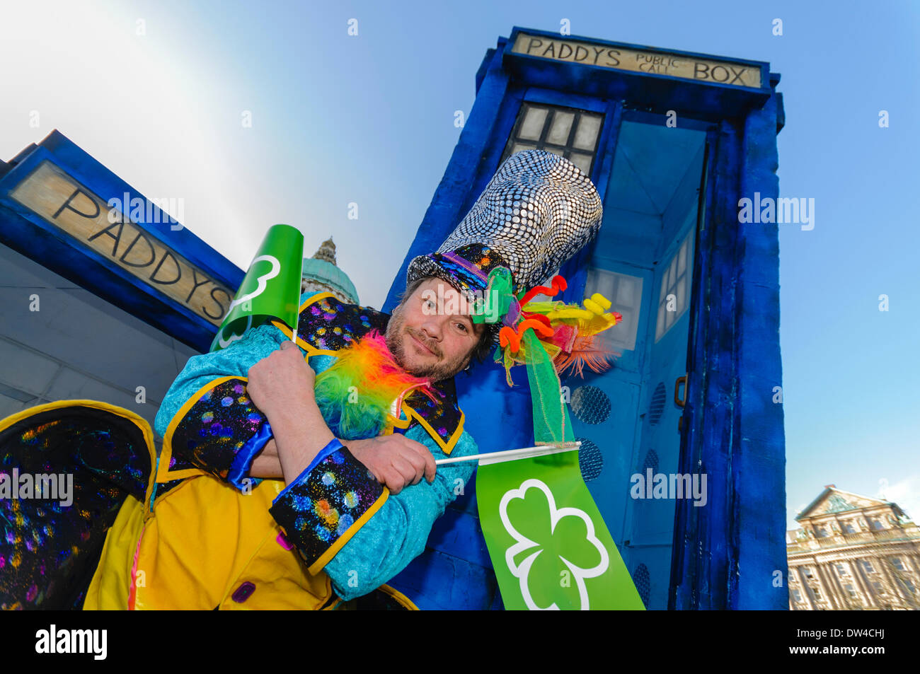 Un homme vêtu de vêtements colorés émerge d'un "Tardis" à un événement de la St Patrick Banque D'Images