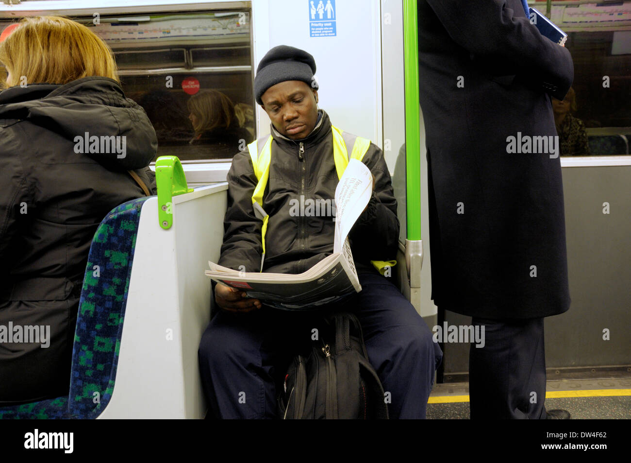 Londres, Angleterre, Royaume-Uni. Homme lisant un journal sur le tube / Londres Métro Banque D'Images