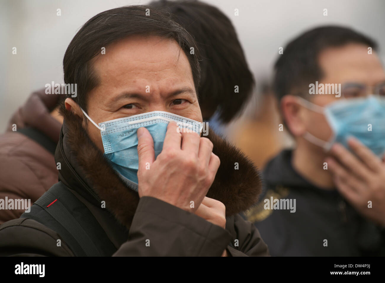 Les touristes portent des masques sur la place Tiananmen à Pékin le 26 février 2014. Banque D'Images