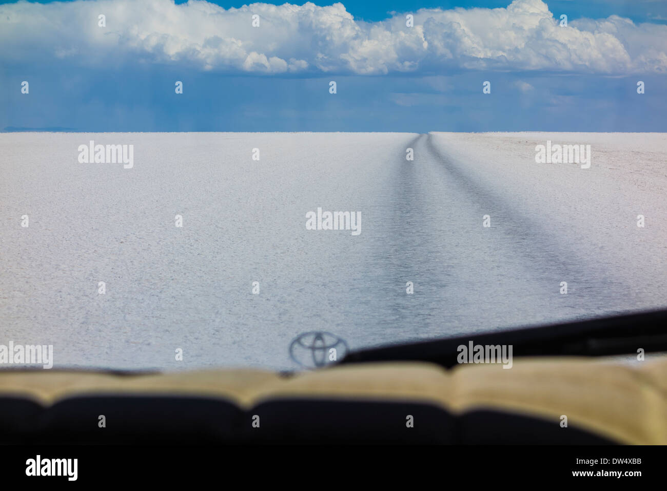 4 roues motrices le long de la piste de sel blanc avec ligne d'horizon et nuages dans l'espace profond et planche de bord et de l'enjoliveur de capot en premier plan Banque D'Images