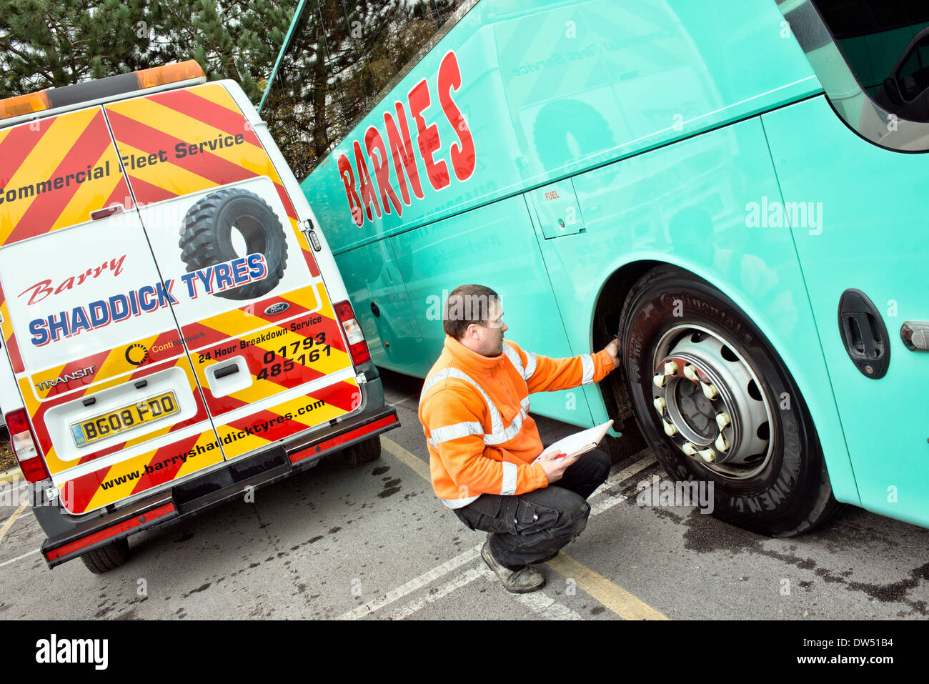 Un mécanicien / Monteur de pneus mobile vérifie un pneu continental des entraîneurs pour bande de roulement au cours d'un service régulier d'inspection et de sécurité Banque D'Images
