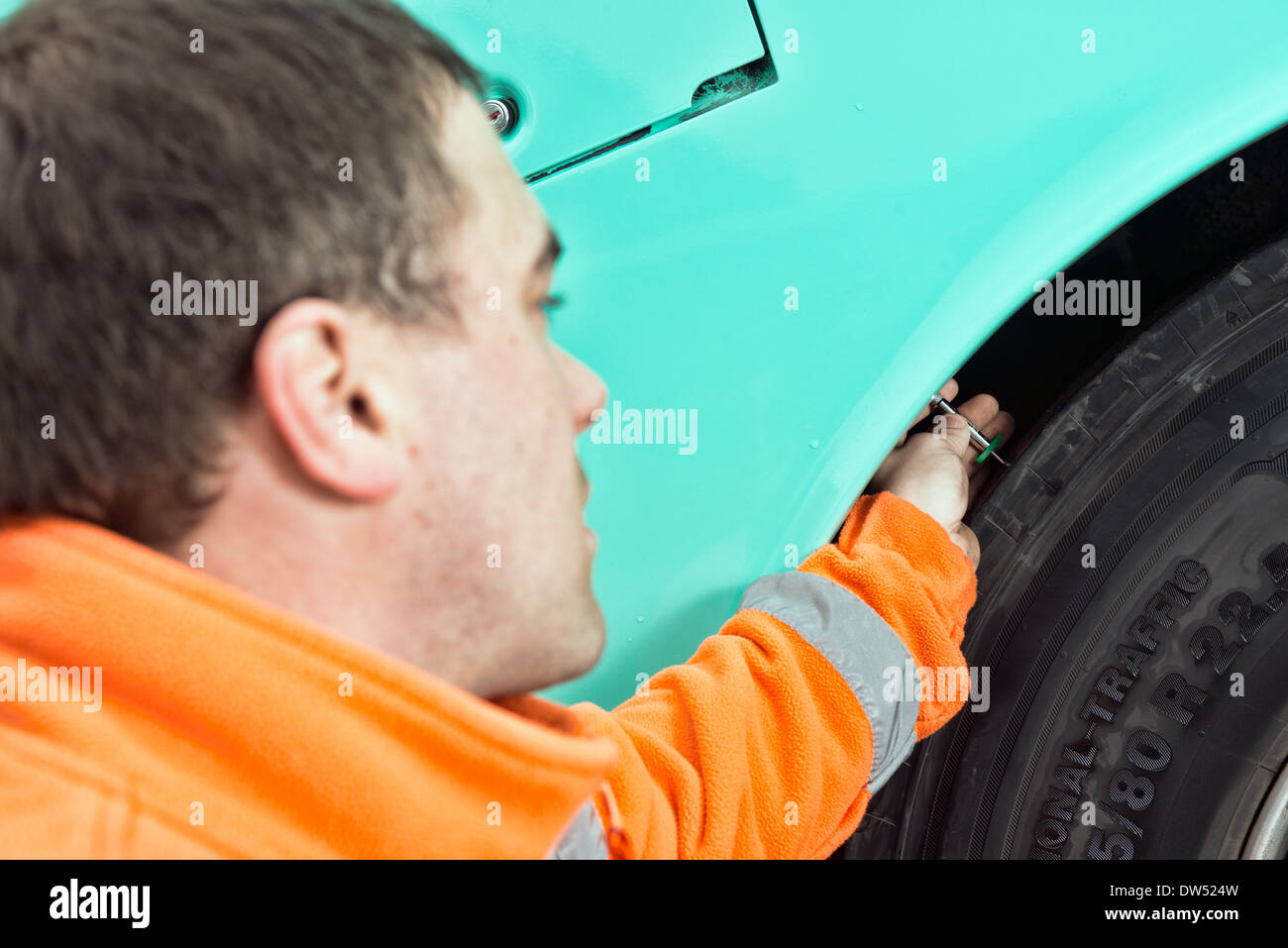 Un mécanicien / Monteur de pneus mobile vérifie un pneu continental des entraîneurs pour bande de roulement au cours d'un service régulier d'inspection et de sécurité Banque D'Images