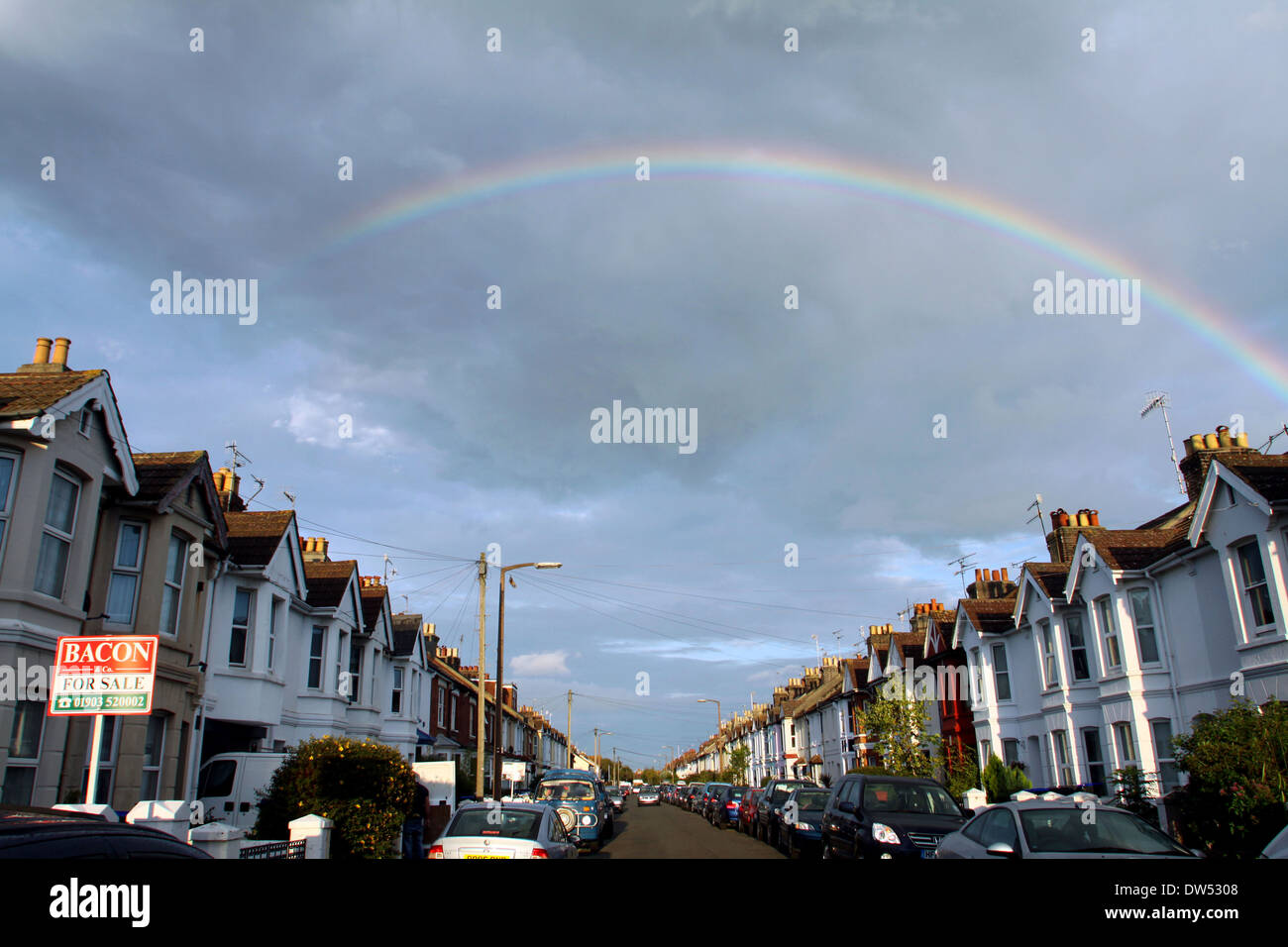 Agent immobilier conseils sont vus dans une rue résidentielle avec de gros nuages derrière et un arc-en-ciel Banque D'Images