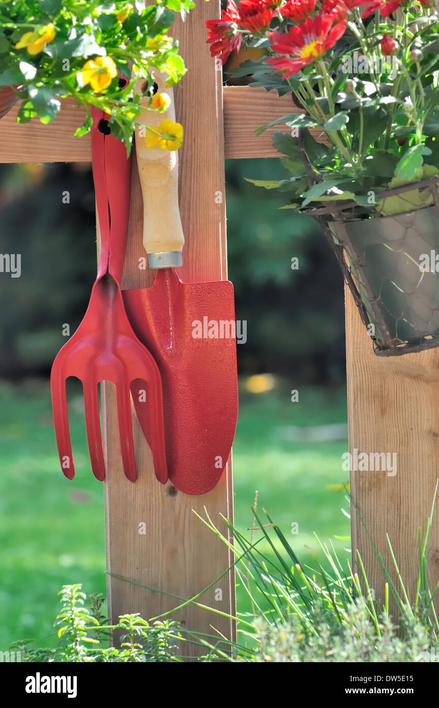 Outils et les pots de fleurs suspendus à une barrière en bois Banque D'Images