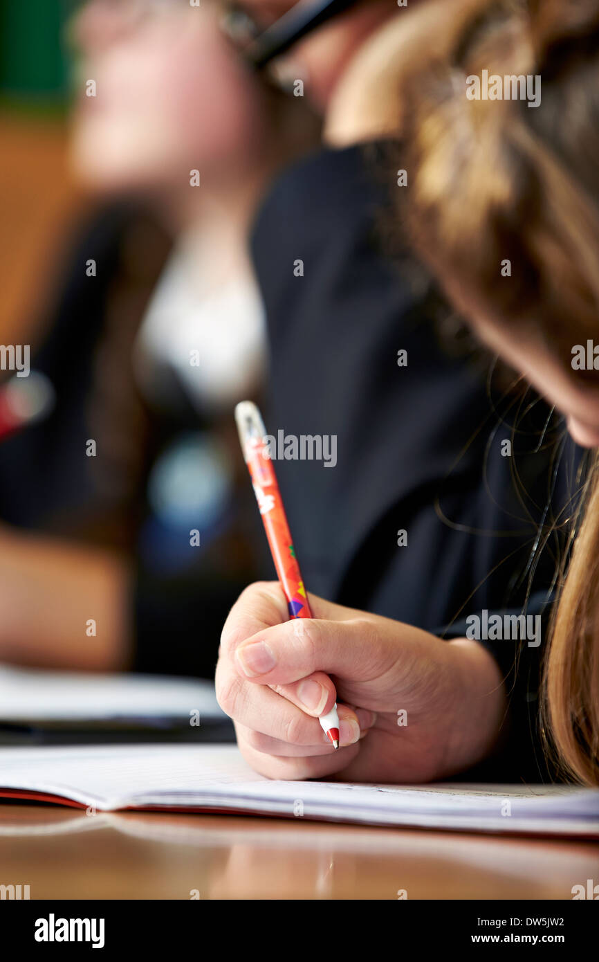 Une fille de l'école écrit dans son livre au cours d'une leçon de l'école Banque D'Images