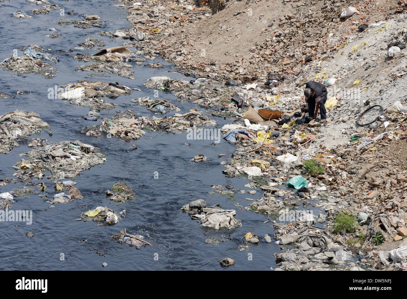 Un homme passant au crible les ordures au bord de la rivière Bagmati sales à Katmandou, Népal Banque D'Images