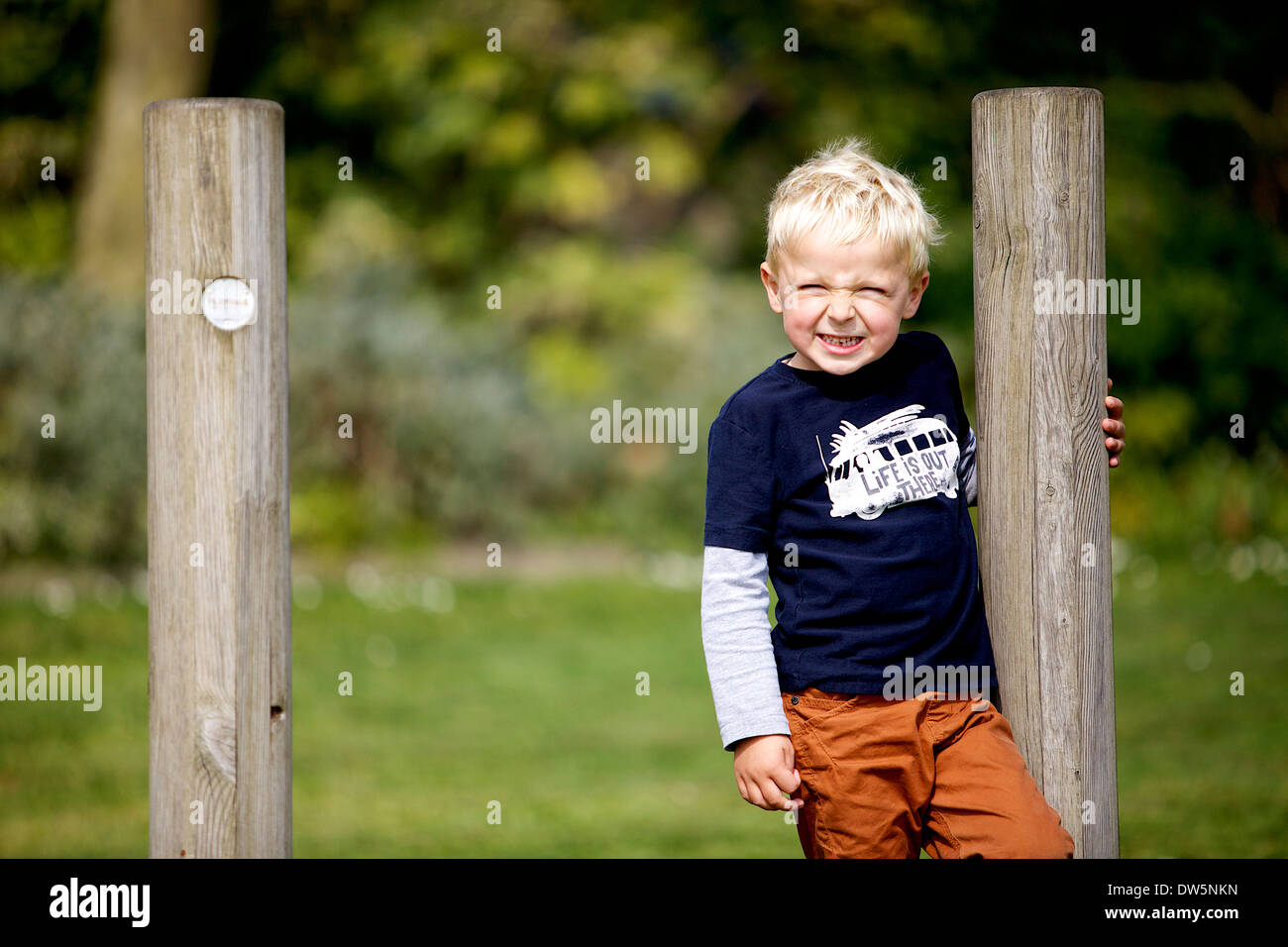 Garçon blond souriant alors que sur les jeux pour enfants Banque D'Images