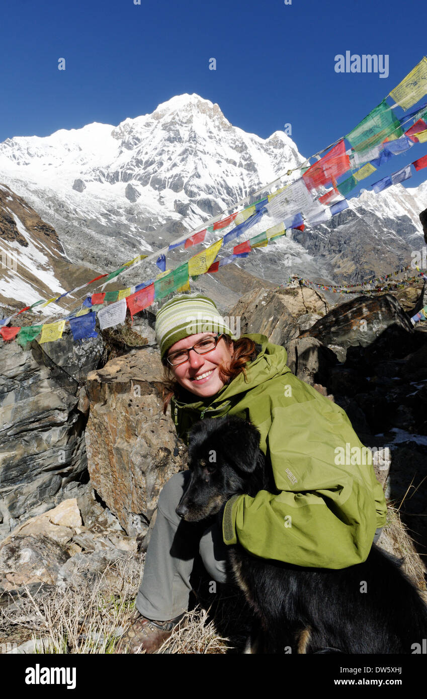 Une dame trekker se lie d'amitié avec un chien local au camp de base de l'Annapurna dans le sanctuaire de l'Annapurna au Népal Banque D'Images