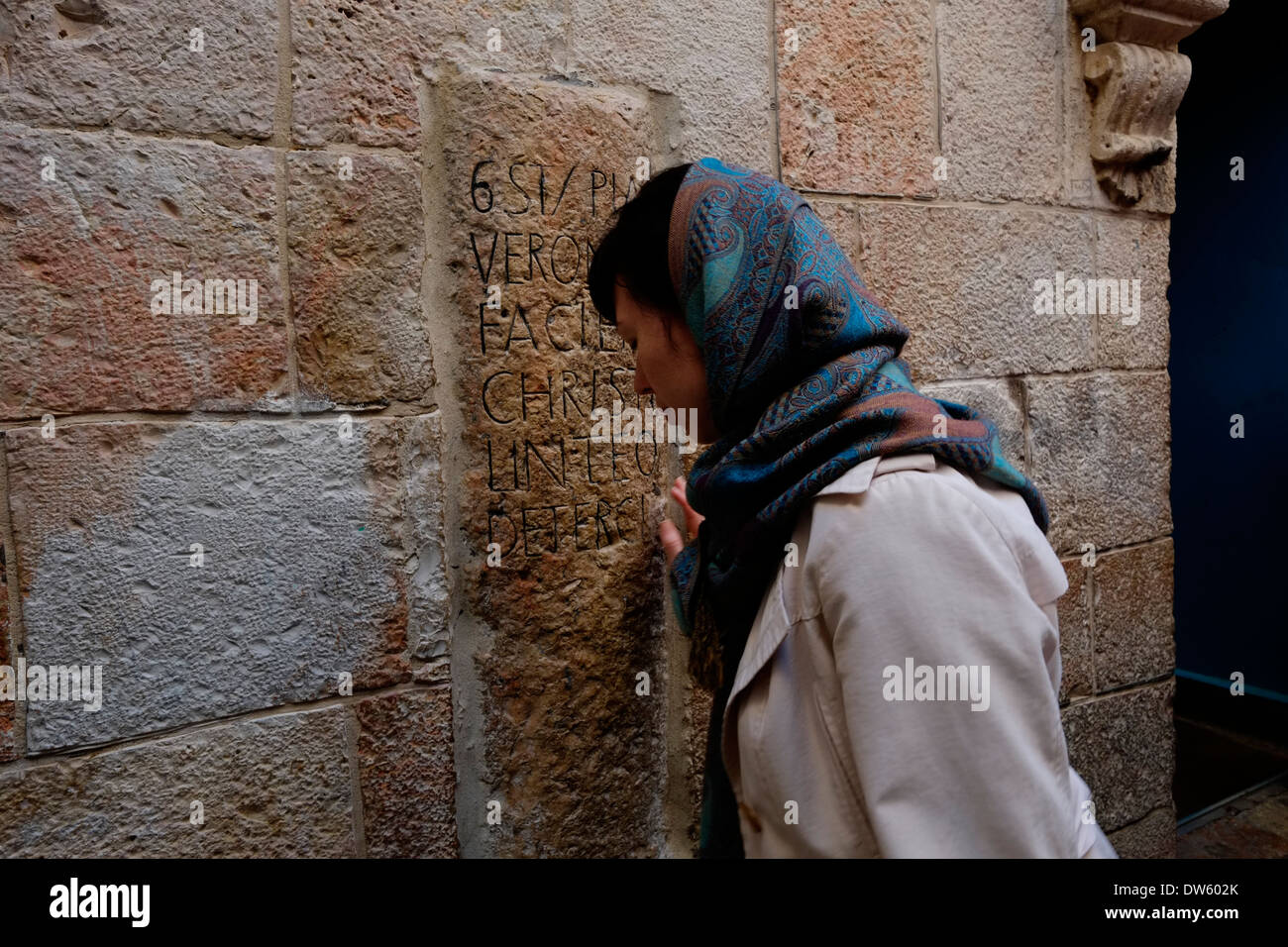 L'est un pèlerin chrétien orthodoxe priant devant un ancien indiquant la sixième station de la croix avec une inscription en latin qui dit Véronique essuie le visage de Jésus en mur extérieur d'une petite chapelle catholique grecque de "La Sainte Face" le long de la Via Dolorosa à Jérusalem Israël Banque D'Images