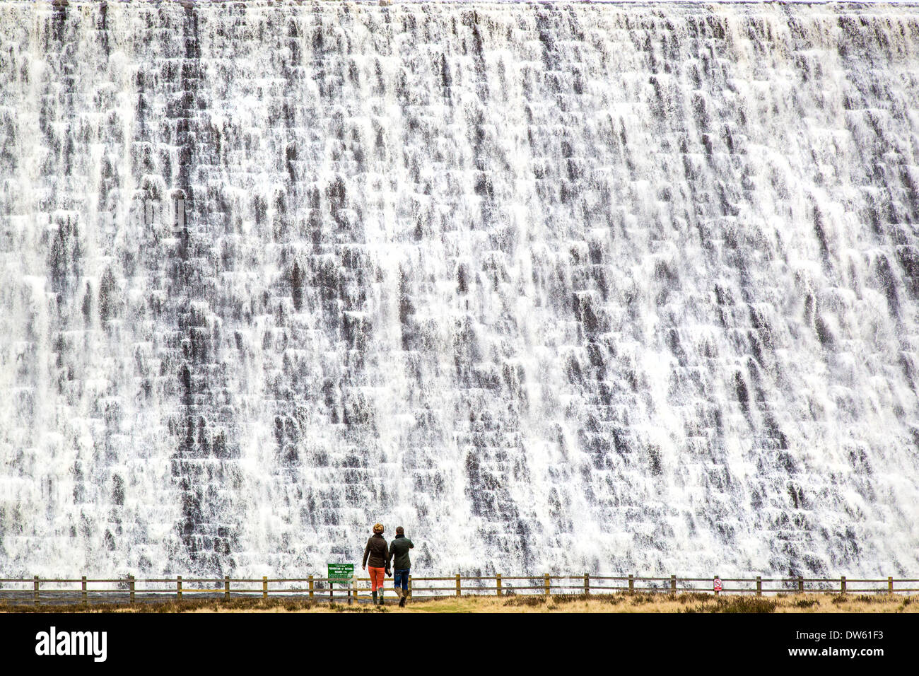 Un couple de l'eau débordant sur la surveillance du réservoir Derwent mur de barrage dans le Derbyshire Peak District après des semaines de forte pluie Banque D'Images