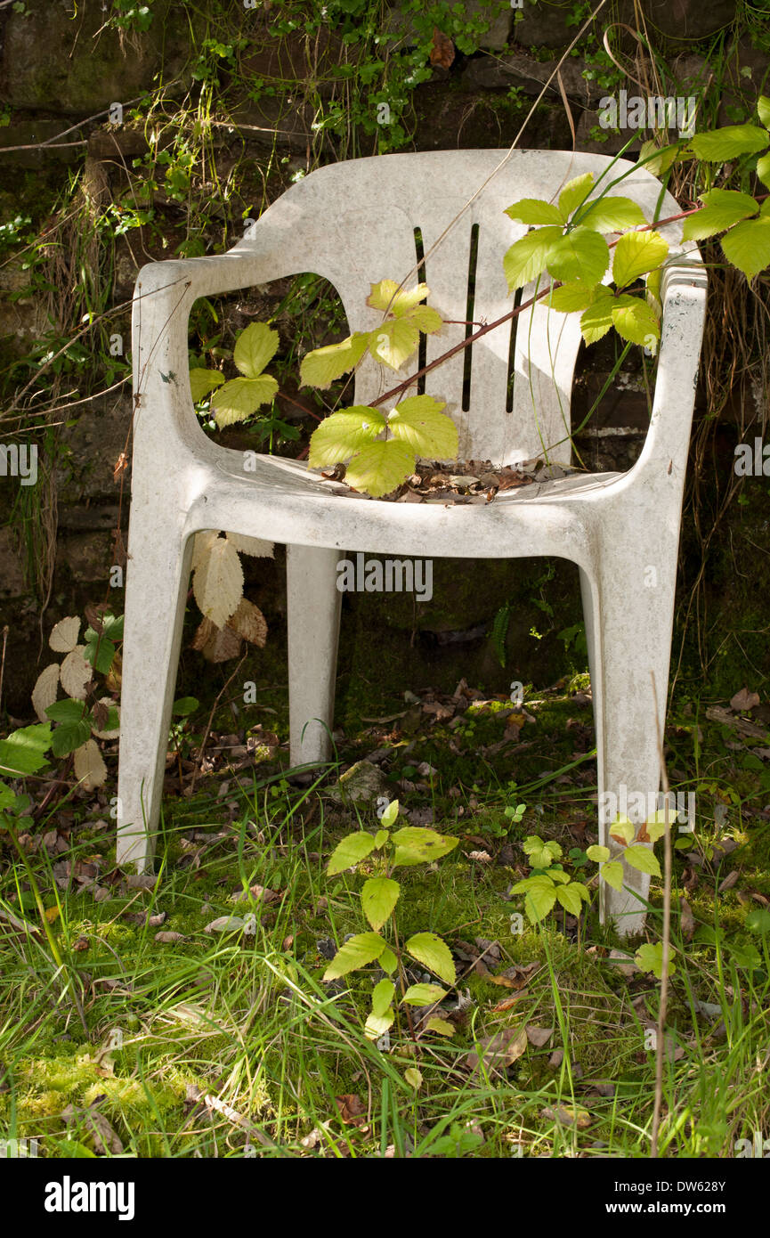 Une vieille chaise de jardin, abandonné dans une basse-cour, ne soient envahies par la végétation. Banque D'Images