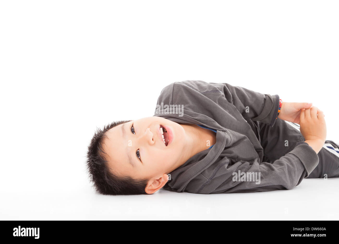 Smiling boy est allongé sur le sol et à la recherche jusqu'en studio Banque D'Images