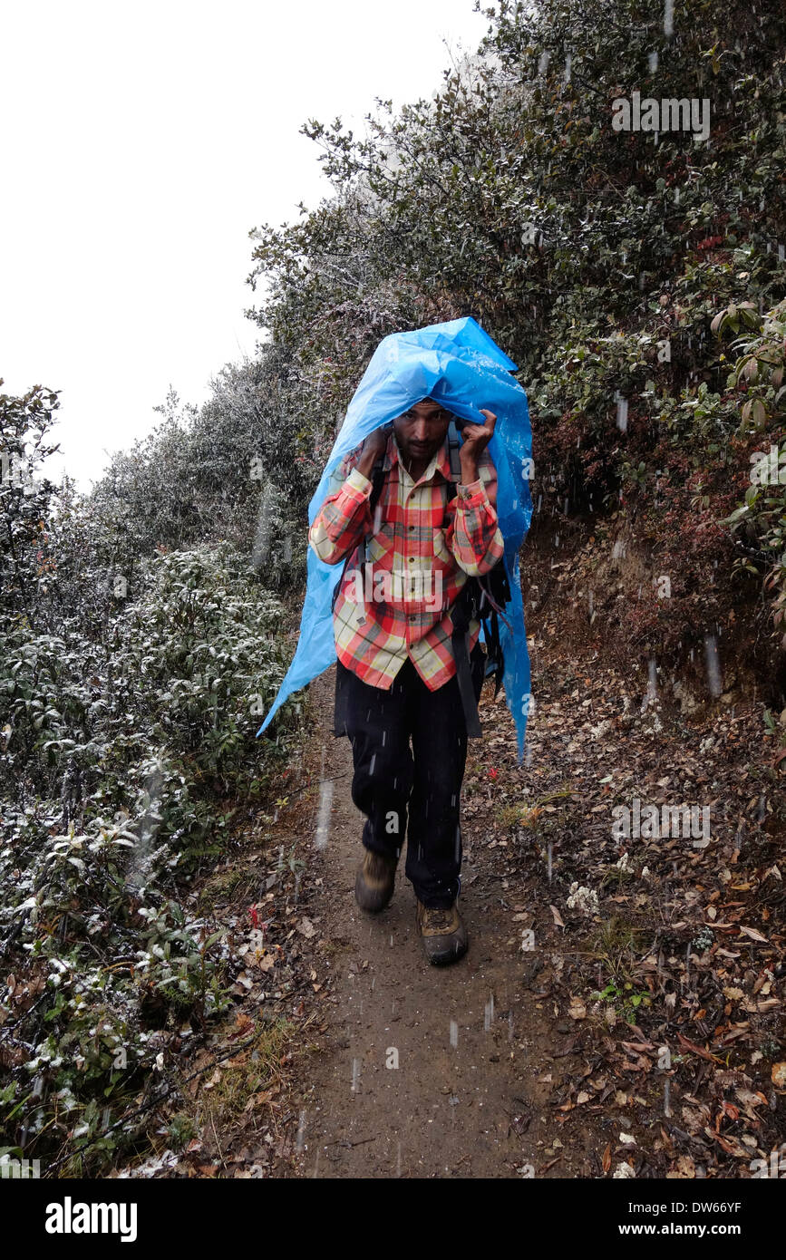 Porter à l'aide de plastique pour le protéger de la neige qui tombe sur un sentier dans la région du Népal Manaslu. Banque D'Images