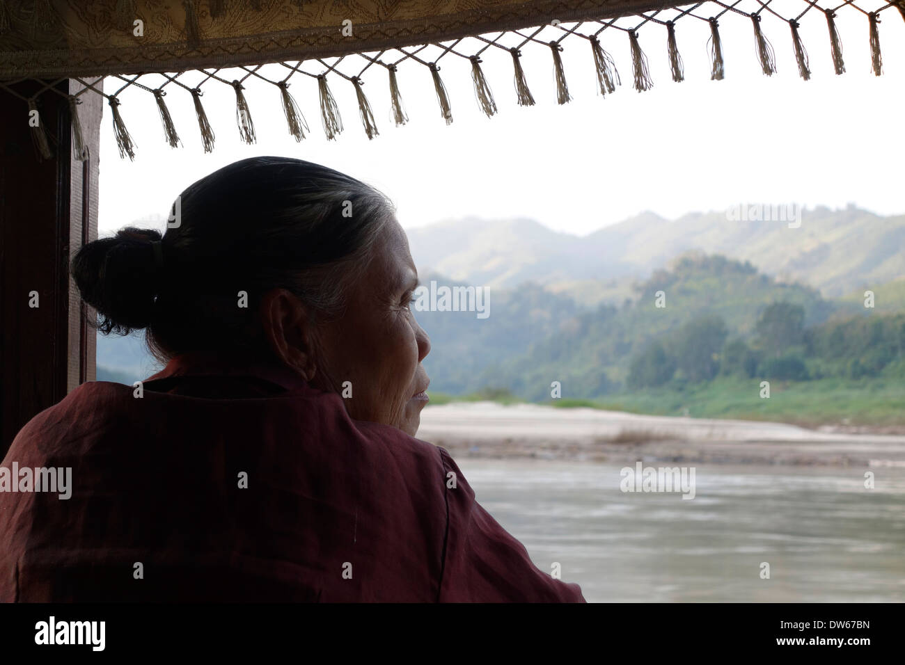 Femme laotienne à partir d'un bateau lent en descendant le fleuve Mékong au Laos. Banque D'Images