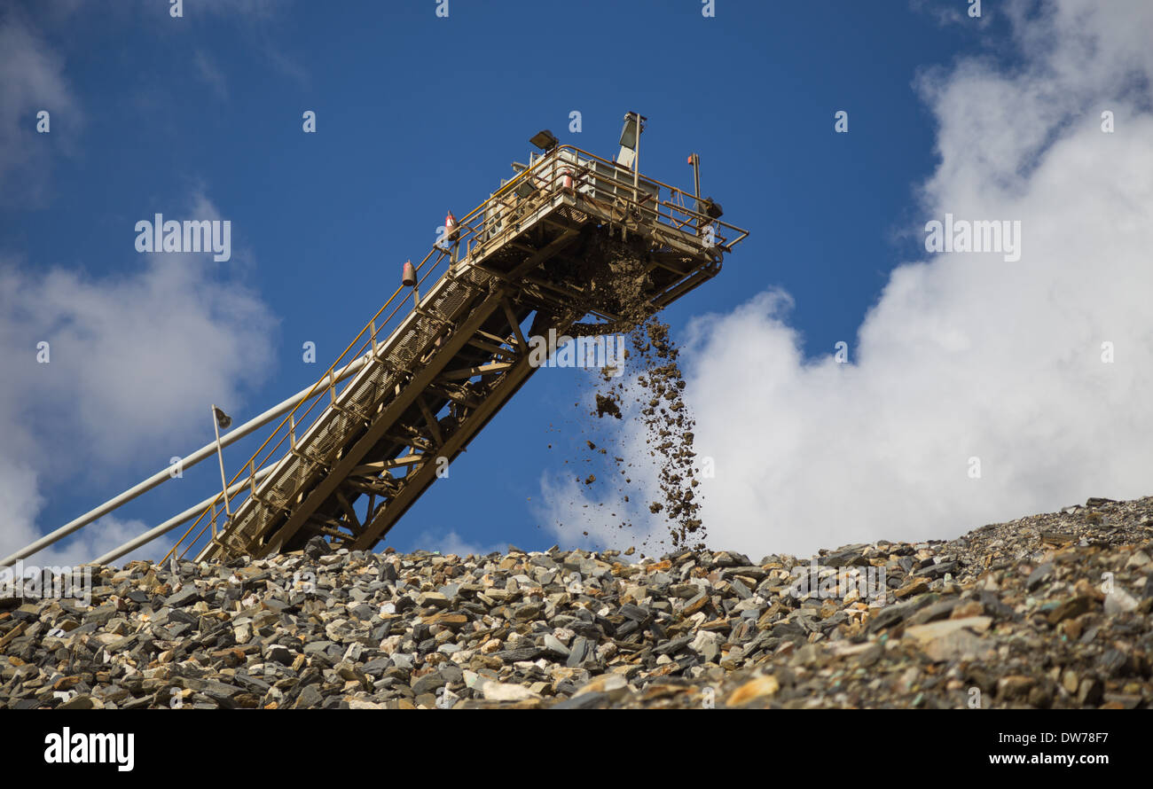 Les chutes de matériaux sur la courroie du convoyeur d'un stock dans une grande mine de cuivre et d'or en Afrique Banque D'Images