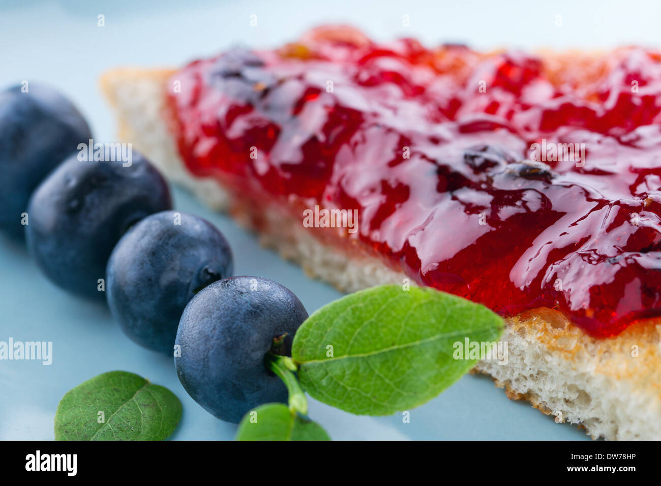 Tranches de pain grillé avec de la confiture de bleuets et de baies fraîches sur fond bleu vintage Banque D'Images