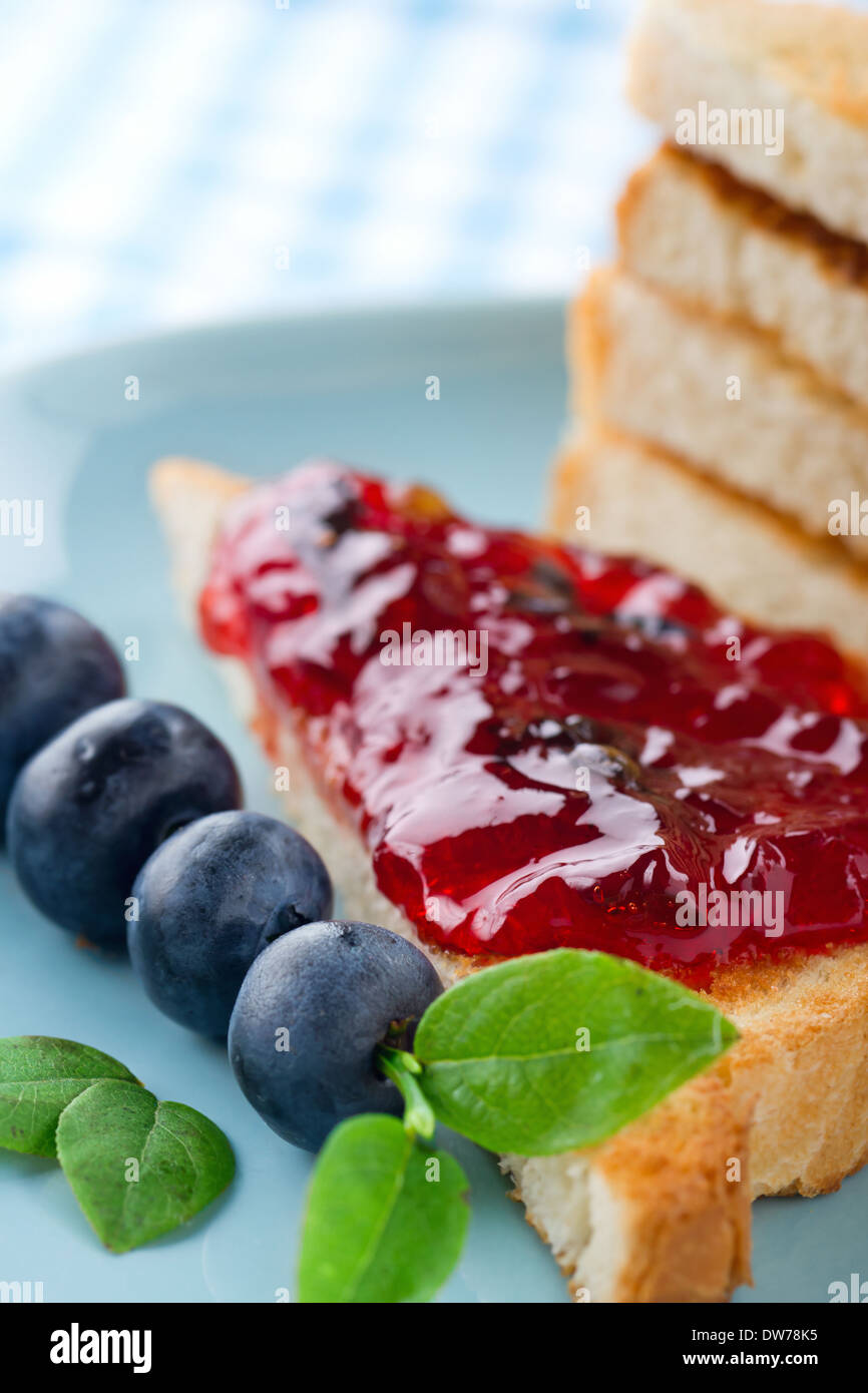 Tranches de pain grillé avec de la confiture de bleuets et de baies fraîches sur fond bleu vintage Banque D'Images