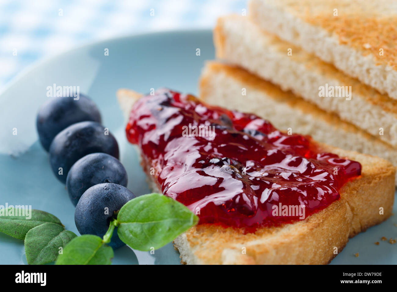 Tranches de pain grillé avec de la confiture de bleuets et de baies fraîches sur fond bleu vintage Banque D'Images