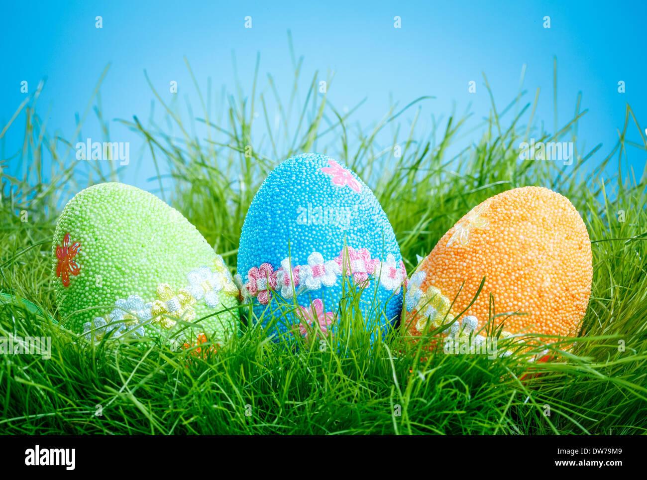 Oeufs de Pâques décorés dans l'herbe sur fond bleu Banque D'Images
