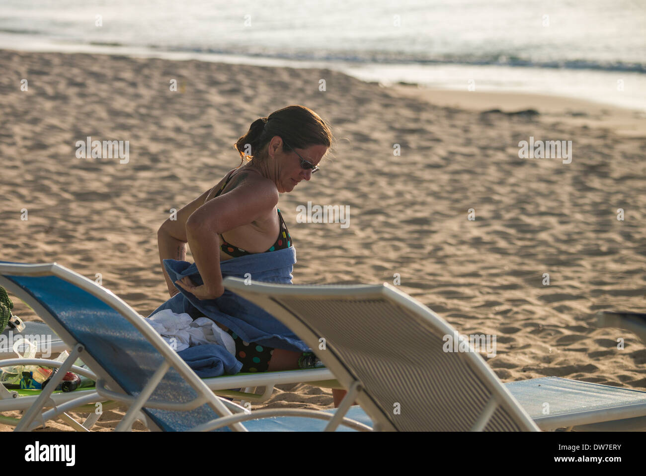 Une femme de race blanche dans la trentaine se détend sur une chaise de plage et sèche au bout de quelques brasses, près du bord de la mer des Caraïbes. Banque D'Images