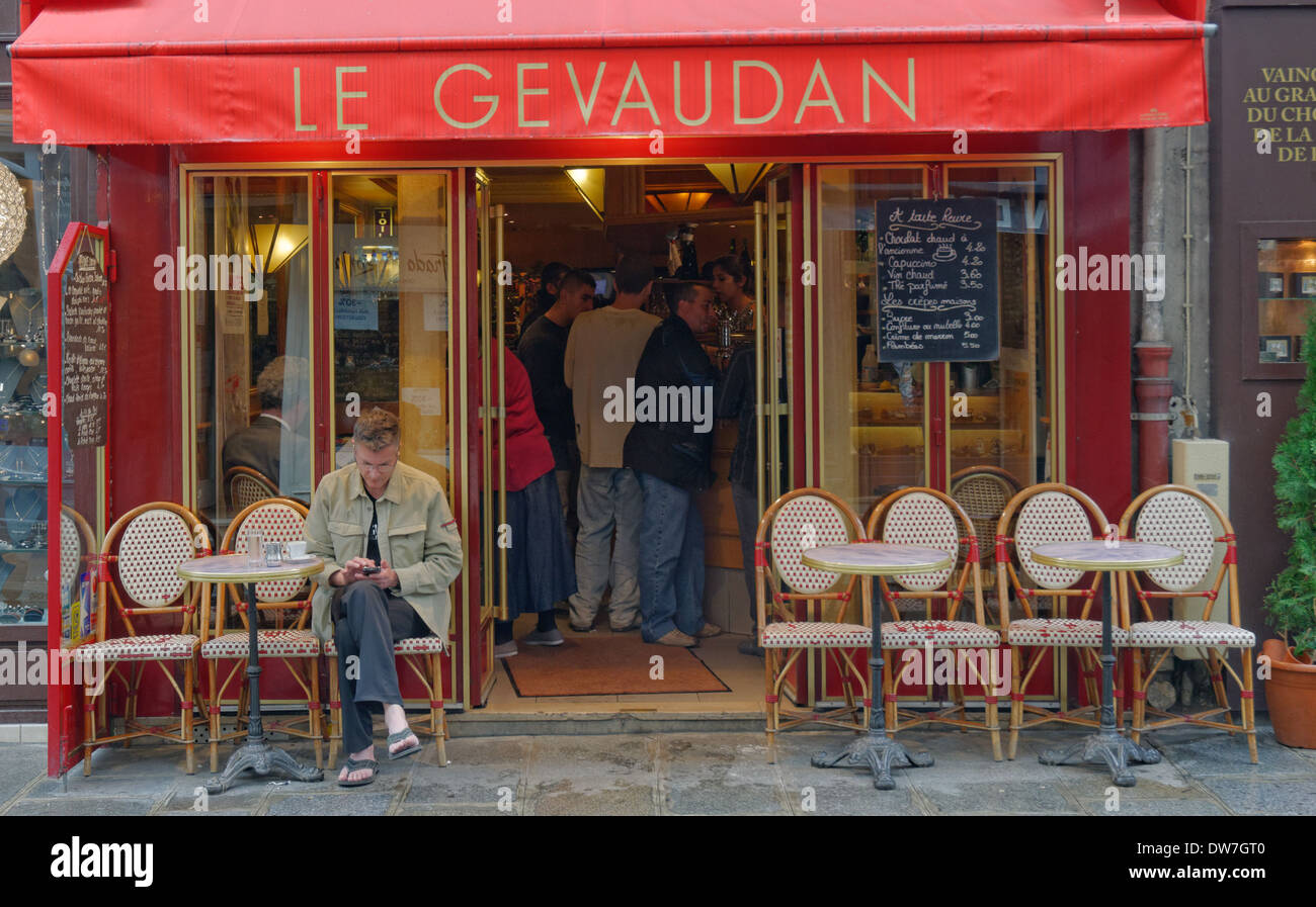 Un homme assis à l'extérieur d'un petit café bar à Paris Banque D'Images