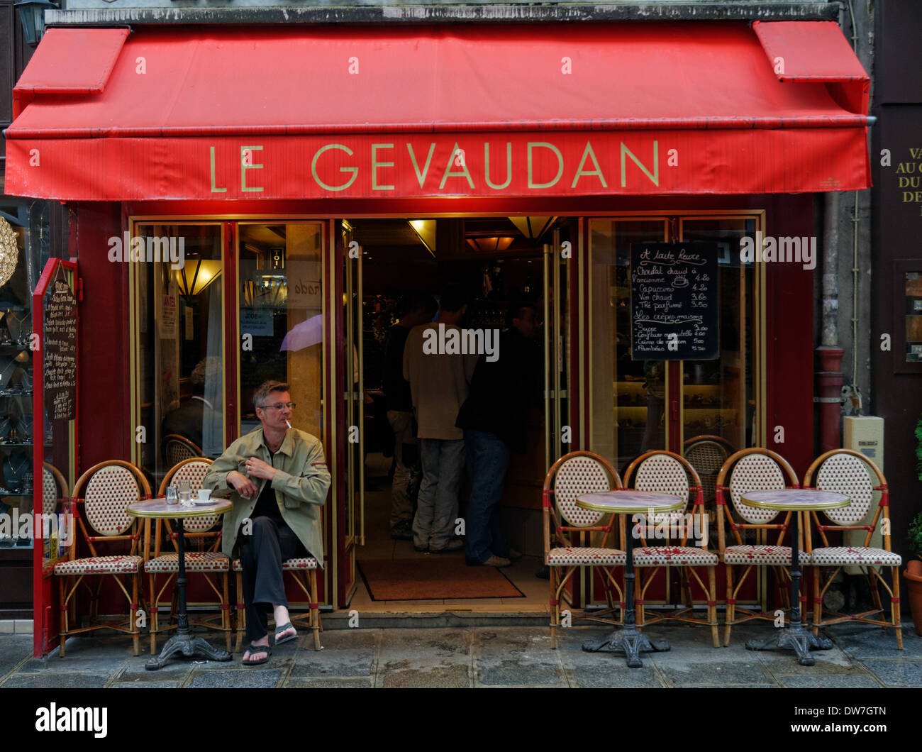 Un homme assis à l'extérieur d'un petit café bar à Paris Banque D'Images
