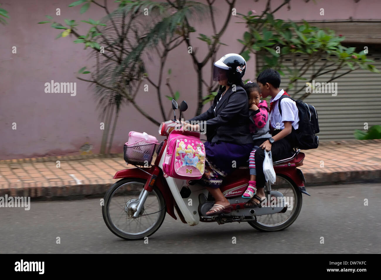 Mère prendre ses enfants à l'école sur une moto dans une rue de Luang Prabang, Laos. Banque D'Images