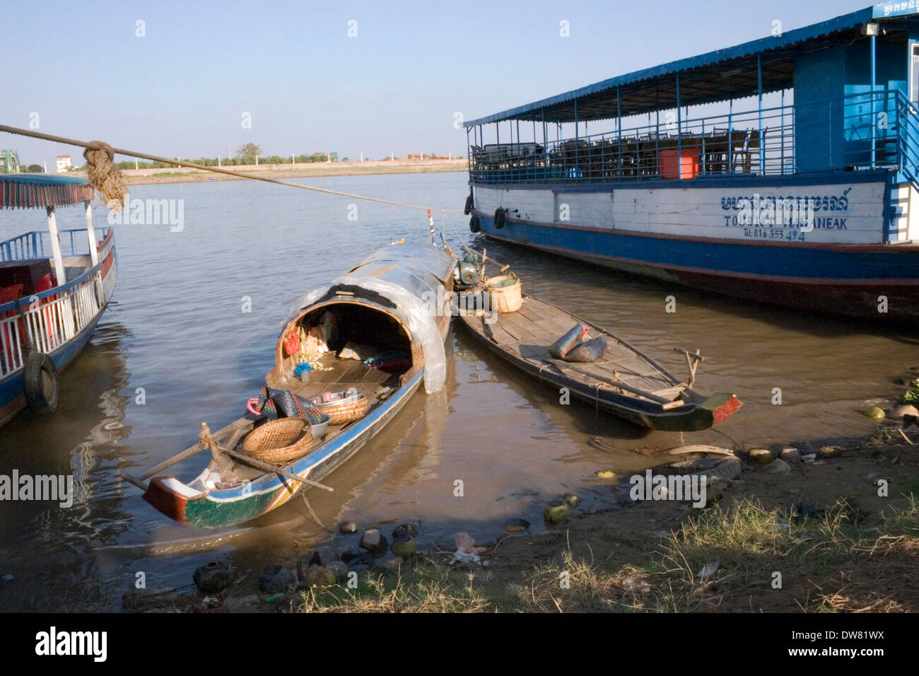 Bateaux de pêche en bois sont amarrés à côté de bateaux de croisière touristique au bord du Mékong à Phnom Penh, Cambodge. Banque D'Images