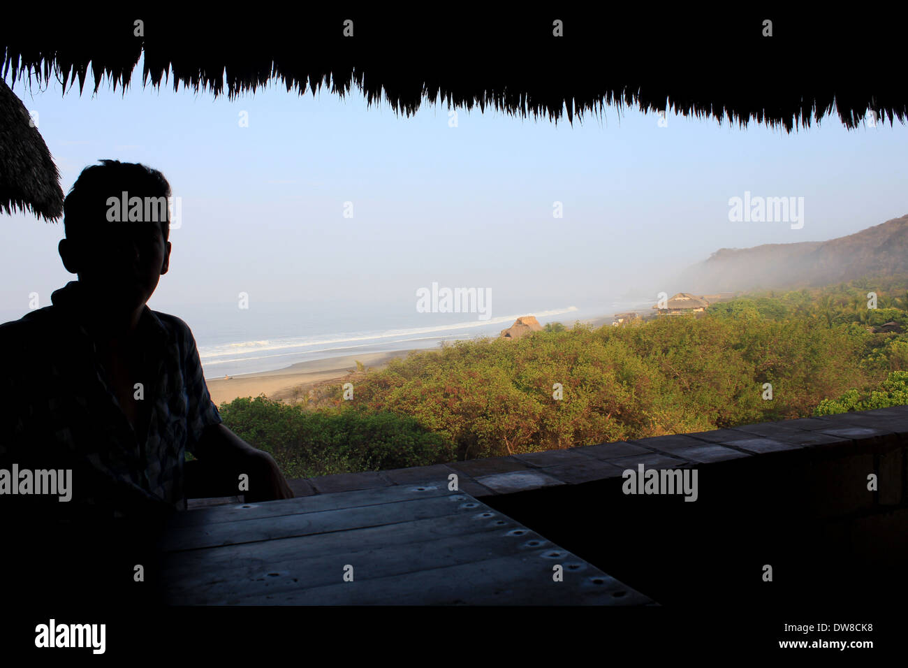 Silhouette d'un garçon à la recherche d'un bungalow écologique au toit de palme sur Mermejita Beach, Mazunte, S. Oaxaca, Mexique Banque D'Images