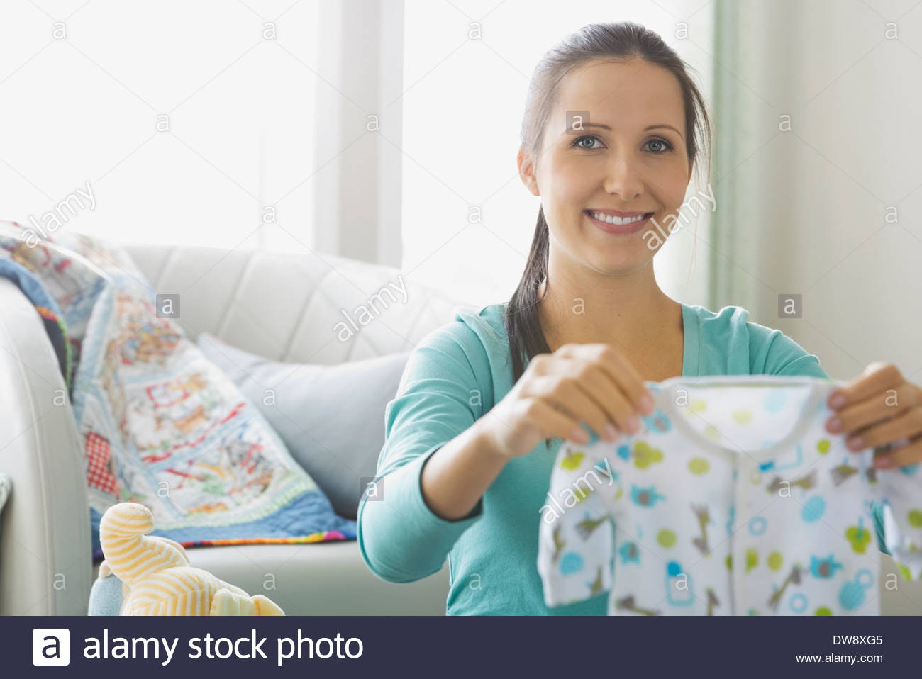 Pregnant woman holding baby onesie in nursery Banque D'Images