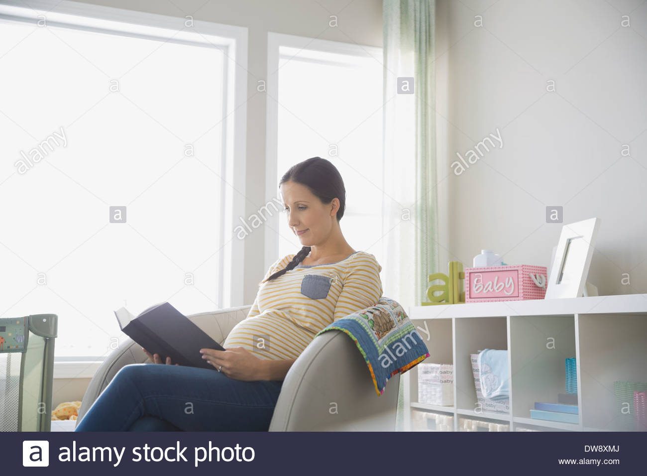 Pregnant woman reading book at home Banque D'Images