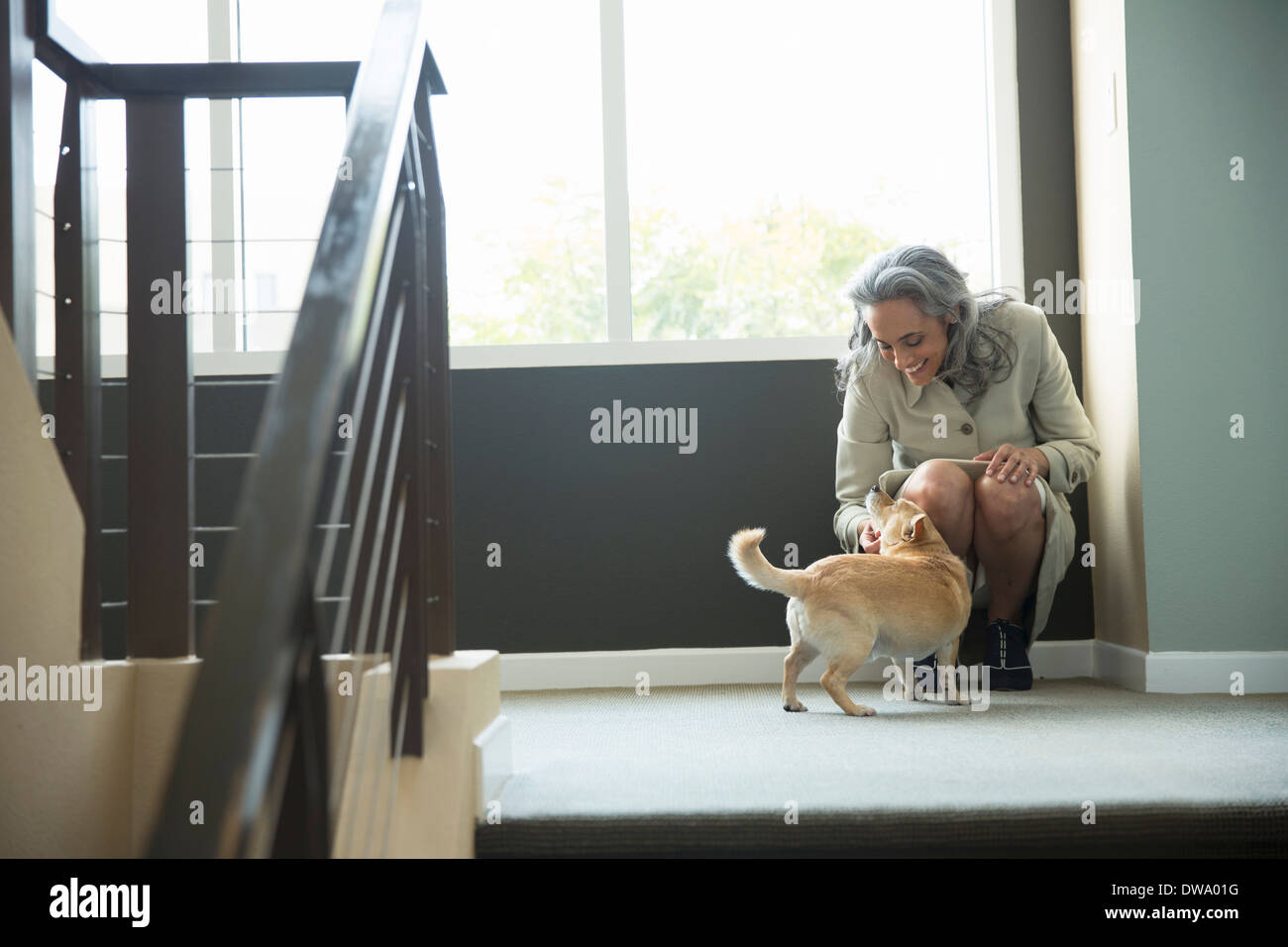 Femme mature de flatter son chien sur escalier Banque D'Images