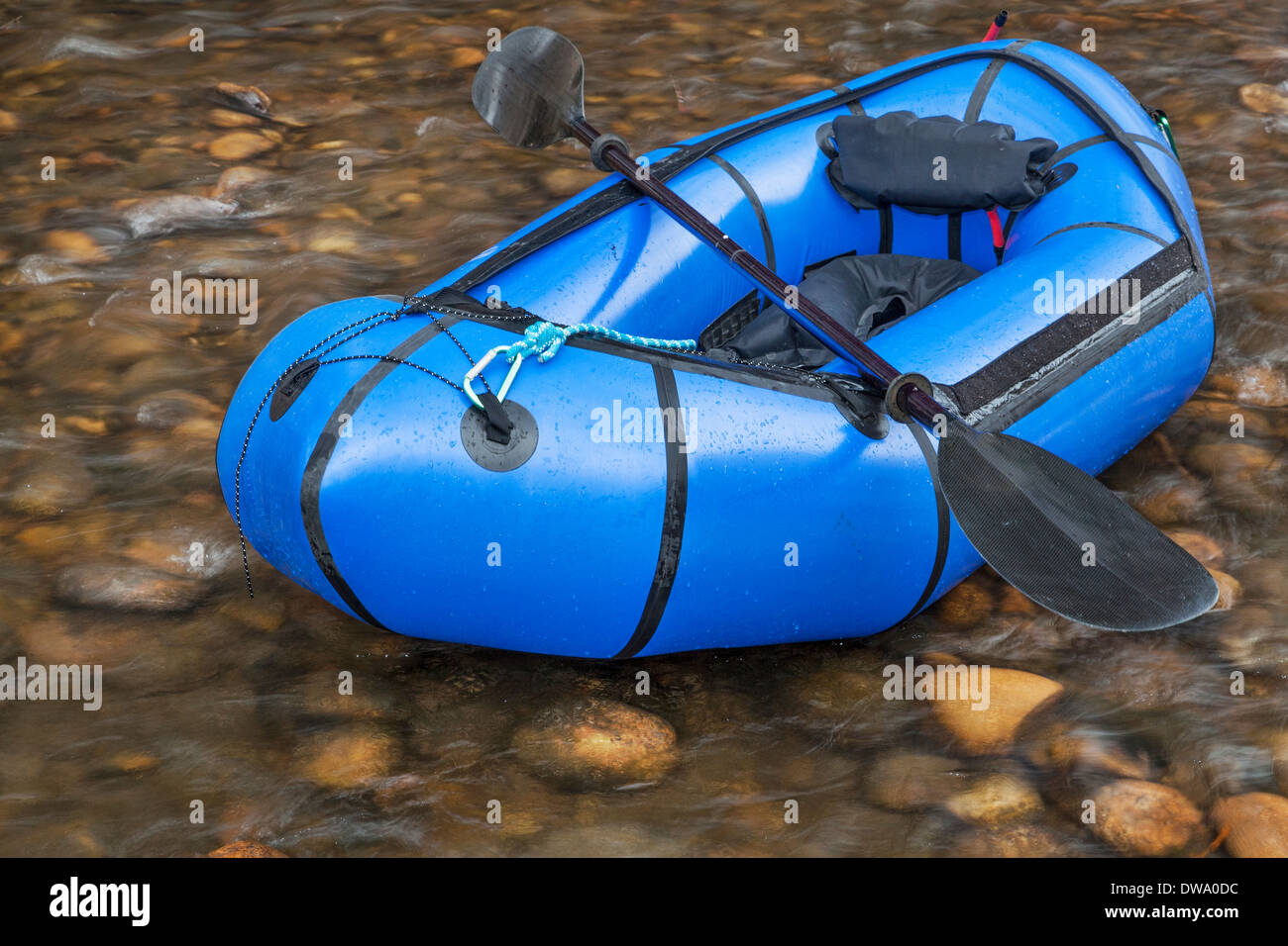 Un bleu (une personne packraft radeau léger utilisé pour la course d'aventure ou d'expédition) avec un kayak paddle contre une rivière peu profonde Banque D'Images