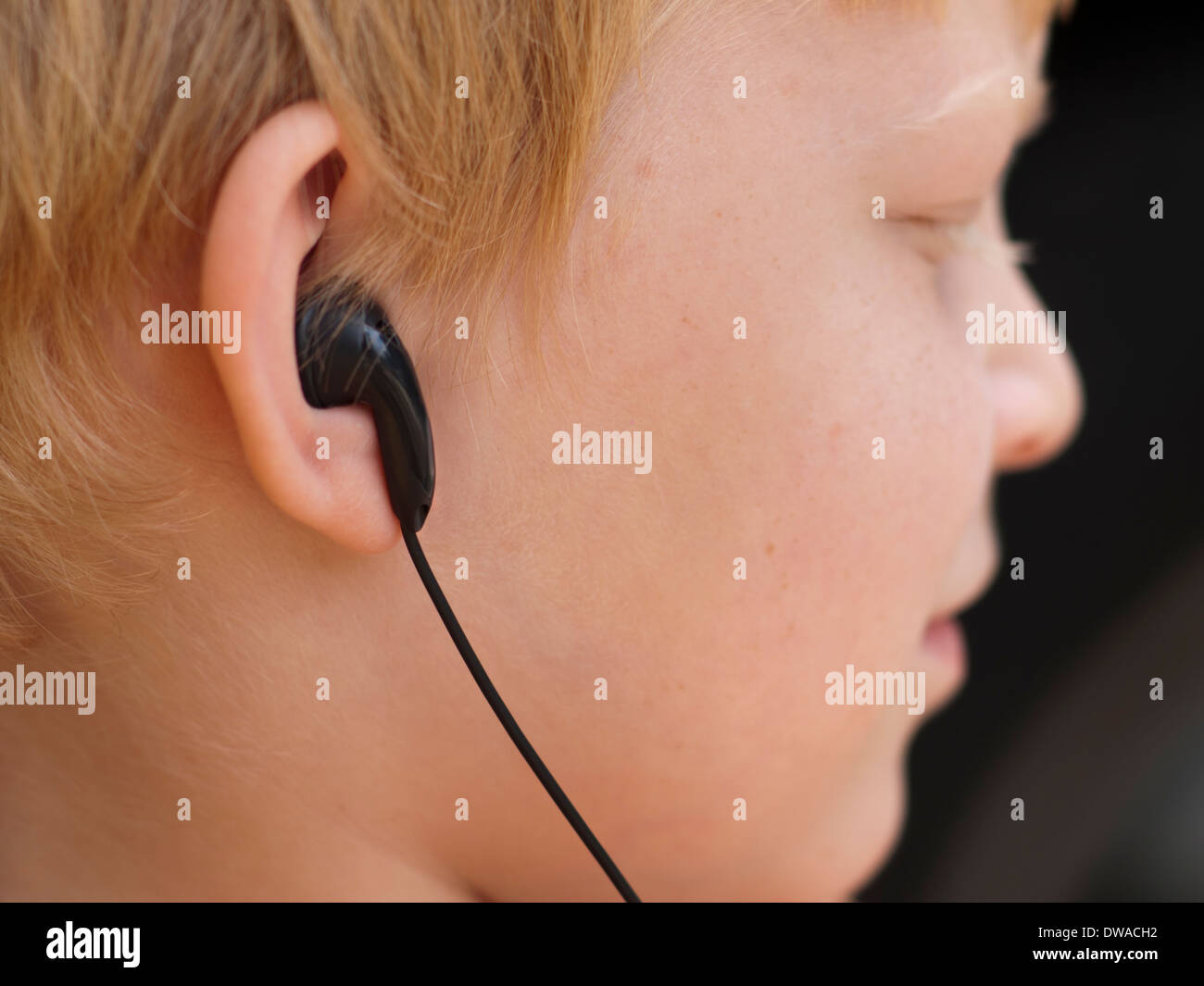 Portrait d'un garçon de 7 ans à l'écoute de son lecteur MP3-Player en utilisant les écouteurs intra auriculaires. Banque D'Images