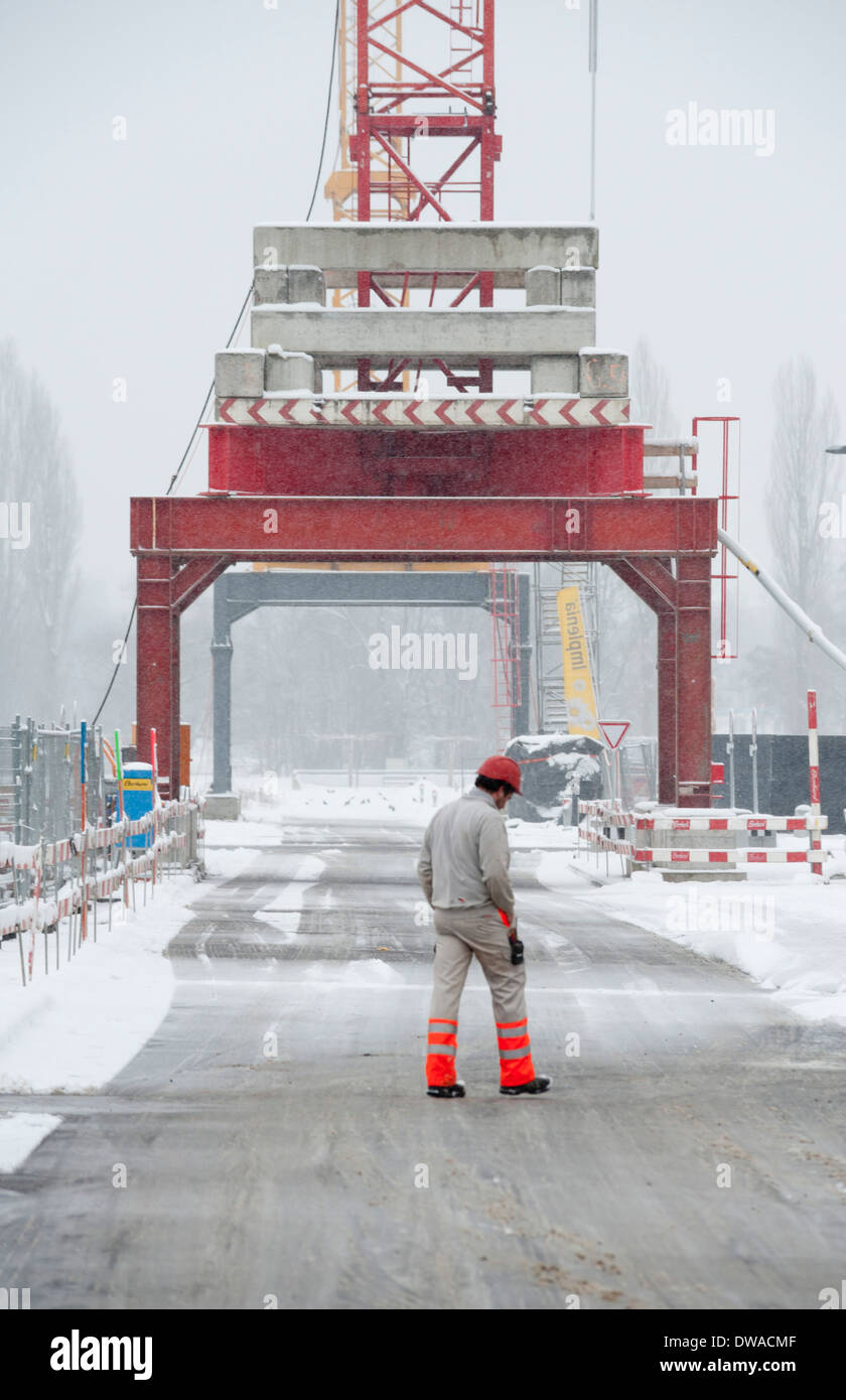 Un travailleur de la construction est de traverser une rue sur un chantier d'hiver de neige à Zurich, Suisse Banque D'Images