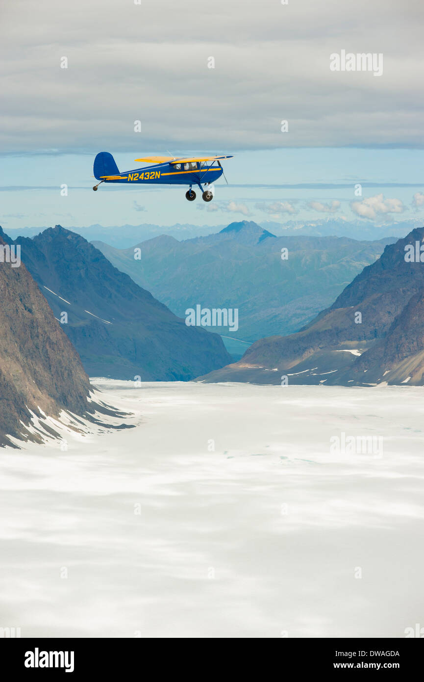 Bleu et jaune un Cessna 140 monomoteur avion volant au-dessus des montagnes Chugach, Glacier Eklutna, Alaska Banque D'Images
