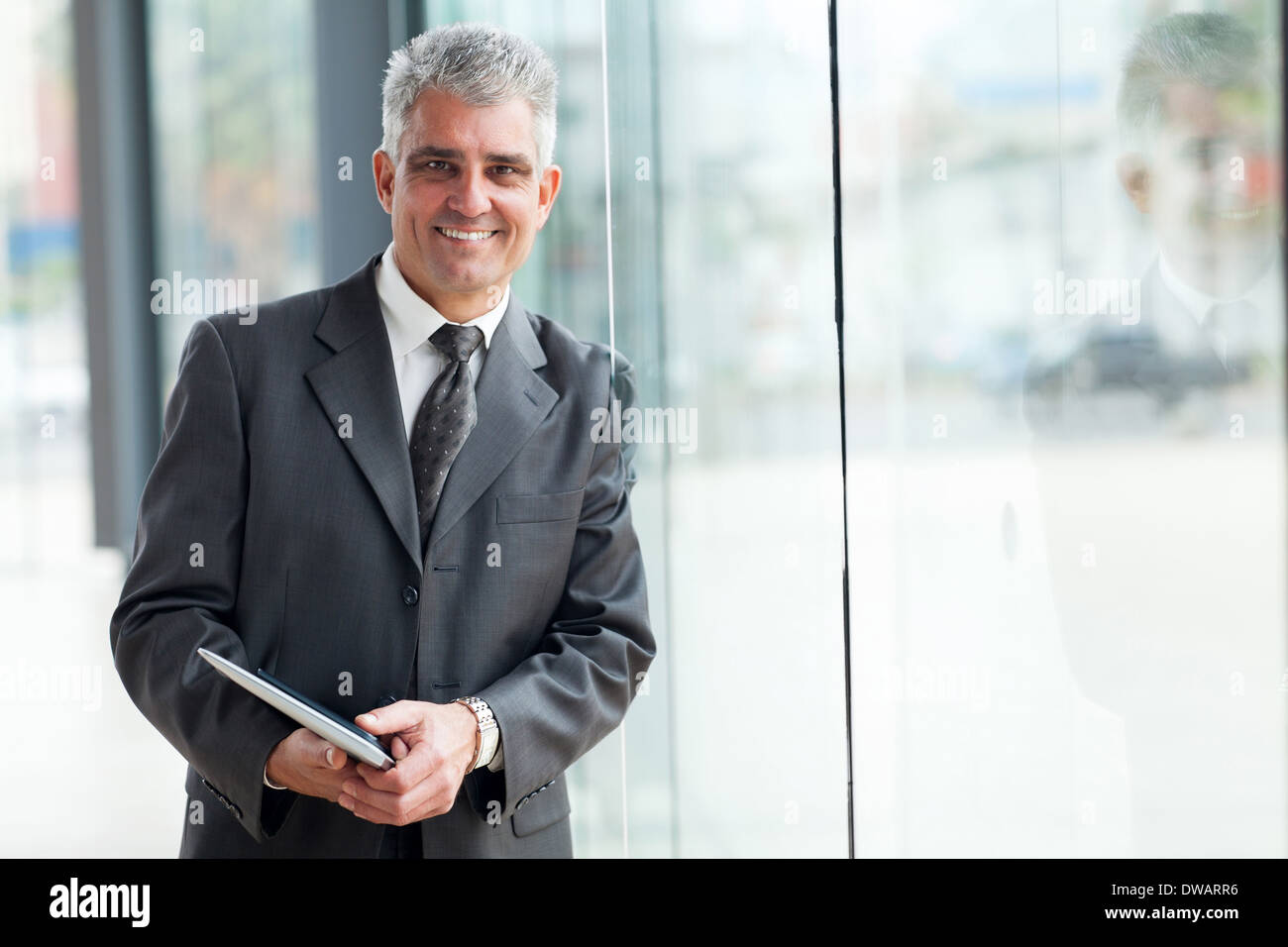 Cheerful senior businessman leaning on office window Banque D'Images