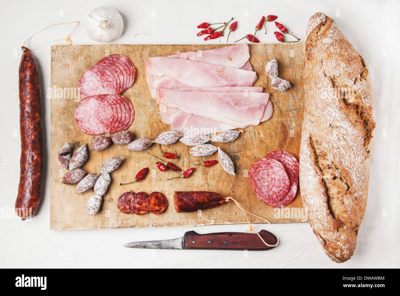 Ensemble de salami et de jambon servi avec du pain frais sur la vieille planche à découper en bois. Banque D'Images